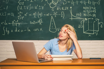 Home schooling. Frustrated female student sitting at the desk in university. Entrepreneur angry and furious with a laptop. Student working on a laptop on some stairs on campus preparing for an exam.