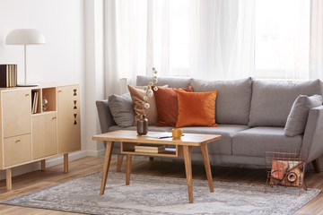 Retro wooden coffee table in front of grey couch in classy living room interior