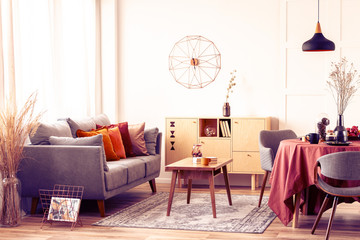 Stylish modern clock on white wall of trendy living room interior