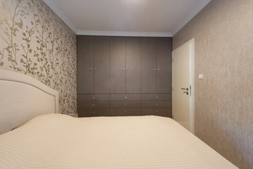 Interior of a beige bedroom with wardrobe wall