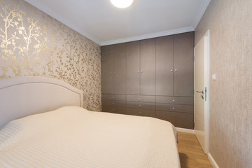 Interior of a beige bedroom with wardrobe wall