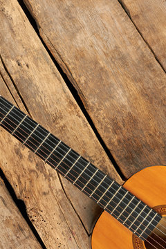 Guitar on old wood and copy space. Acoustic guitar on rustic wooden boards, cropped image. Classical equipment of musician.