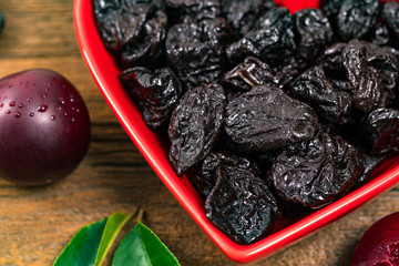 Dried Plums Pitted Prunes in Heart Shaped Bowl Background. Selective focus.