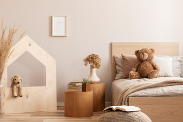 Elegant kid's bedroom with wooden furniture and toys, real photo with copy space on empty wall