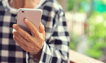 close up senior asian woman holding smartphone and try to using application or watching media on website in weekend , lifestyle relaxation with technology concept