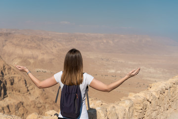 Fototapeta na wymiar young woman with arms raised looking the panorama over the desert in israel