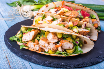 Tacos with vegetables, avocado and chicken breast on a slate dish - traditional mexican appetizer