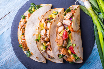 Tacos with vegetables, avocado and chicken breast on a slate dish - traditional mexican appetizer