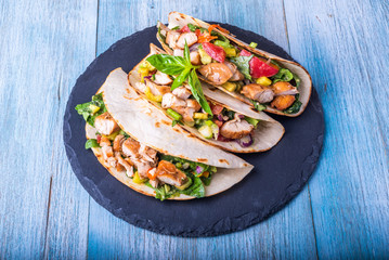 Tacos with vegetables, avocado and chicken breast on a slate dish - traditional mexican appetizer