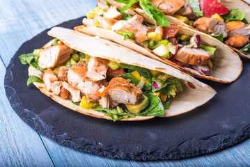 Tacos with vegetables, avocado and chicken breast on a slate dish - traditional mexican appetizer