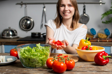 young girl prepares a vegetarian salad in the kitchen, she adds sliced ingredients to the plate, the process of preparing healthy food