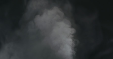 water vapor cloud comes from below over black background with motion blur