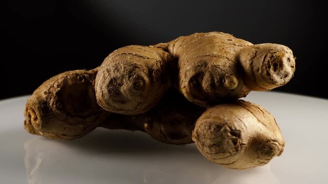 Fresh ginger root on white plate, black background. Healthy eating