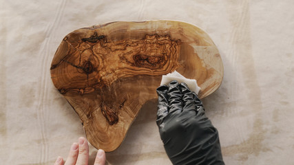 woodworker applying oil finish to olive wood board from above
