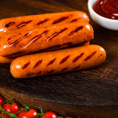 Grilled Smoked Hot Dogs Sausages on Wooden Background. Selective focus.