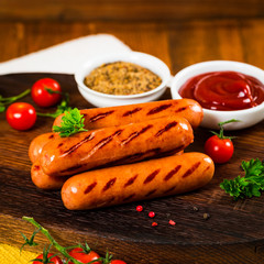 Grilled Smoked Hot Dogs Sausages on Wooden Background. Selective focus.