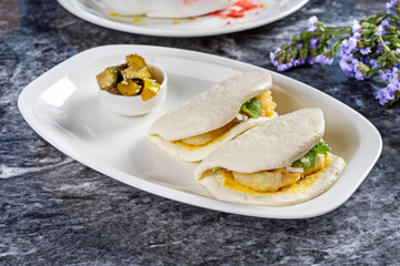 Close up view on bao with shrimp. Gua bao, steamed buns served on white plate. Taiwan's traditional food Gua Bao on marble table. Asian sandwich steamed. Asian fast food. Seafood