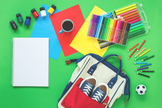 Assorted office or school sets of multicolored stationery school bag backpack, sneakers and coffee on green background. Flat lay copy space. back to school or creative design education craft concept.