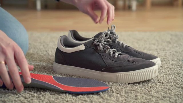 woman inserts orthopedic insoles into shoes