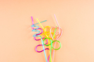 Colorful party cocktail straws on orange