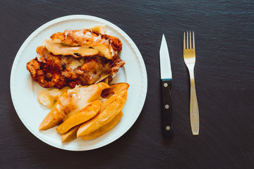 Poached potatoes with cordon bleu on a slate – Homemade dinner with chicken meat and boiled vegetables served on porcelain dish next to cutlery