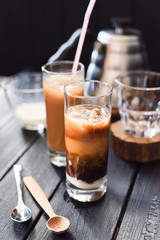 Iced layered coffee with coconut milk in tall glasses on black background