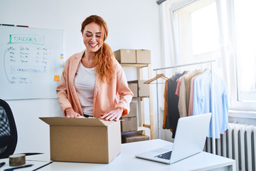 Small online business owner preparing deliveries in office and smiling