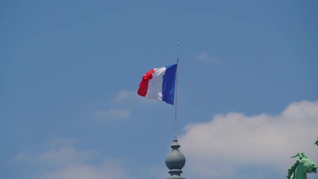 French flag on building waving in the wind on a sunny day in Paris, France, July 3th 2019