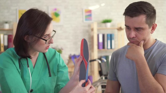 Orthopedic doctor tells the man about orthopedic insoles close up
