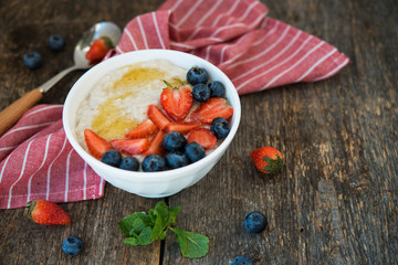 Healthy Breakfast oatmeal bowl with berries and honey on rustic wooden background