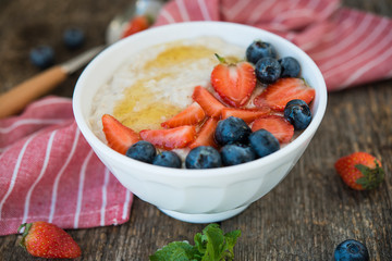 Healthy Breakfast oatmeal bowl with berries and honey on rustic wooden background