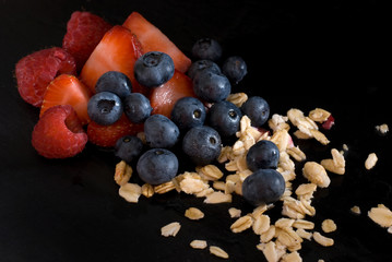 Delicious Juicy Fresh Fruits with Oats on Black Background