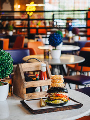Big burger with beef cutlet, black bun, onion rings