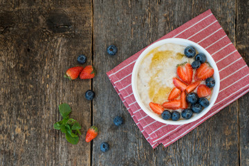 Healthy Breakfast oatmeal bowl with berries and honey on rustic wooden background