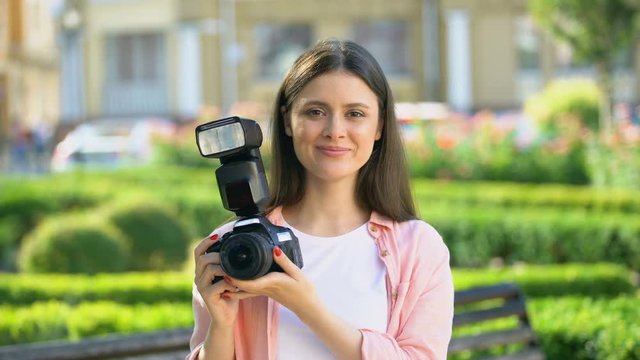 Female photographer taking photos with camera in park, lessons for beginners