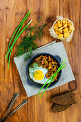Fried eggs with mushrooms in a cast iron pan. Traditional dish of russian cuisine.