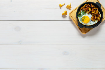 Fried eggs with mushrooms in a cast iron pan. Traditional  dish of russian cuisine, copy space, flat lay.