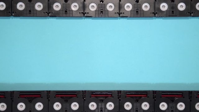 Analog film screen concept made of vintage mini DV cassette tapes used for filming back in a day. Pattern made of plastic video tapes on blue background