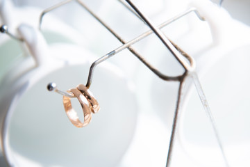 wedding rings and white glasses hanging on the hook from the stand for cups and plates