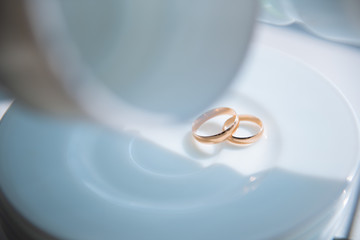 wedding rings on a white plate that lie in a stack on a stand with hanging white circles