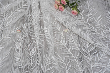 White wooden background with white spring flowers roses and lace ribbon. Happy womans day. The texture of lace on wooden background.