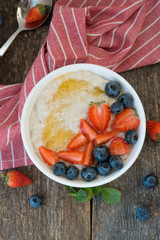 Oatmeal with summer berries and honey on wooden background