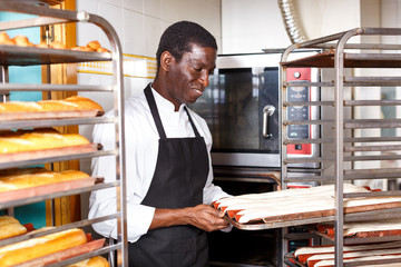 Bakery worker preparing raw baguette dough for baking