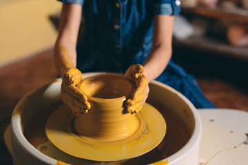 Fototapeta na wymiar Pottery workshop. A little girl makes a vase of clay. Clay modeling