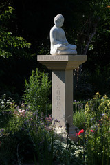 Buddha-Statue auf einer Steinsäule im Garten