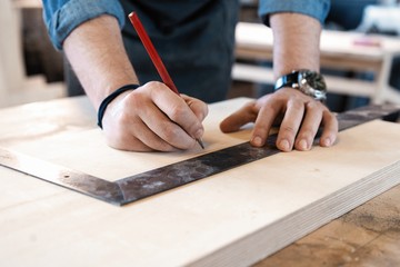 Carpenter working on woodworking machines in carpentry shop. A man works in a carpentry shop.