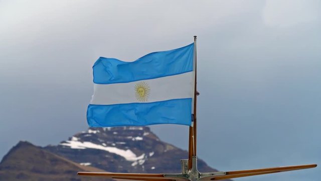 Argentinian flag on small boat waving in the wind with mountain in background