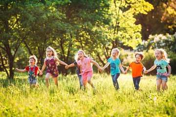 Large group of kids, friends boys and girls running in the park on sunny summer day in casual clothes . © davit85