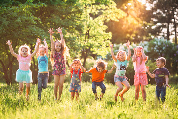 Group of friends running happily together in the grass and jumping.