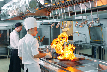 Modern kitchen. Cooks prepare meals on the stove in the kitchen of the restaurant or hotel. The...